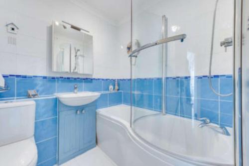 een blauwe en witte badkamer met een bad en een wastafel bij Hove Actually with spectacular sea views in Hove