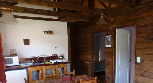 a kitchen with wooden walls and a table and chairs at Cabañas El Puesto Sur in El Chalten