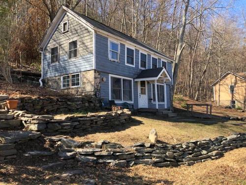 a house with a stone wall in front of it at Relax Like It's 1800! in Pond Eddy