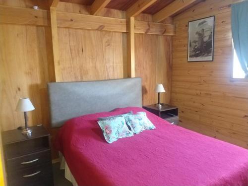 a bedroom with a pink bed with two pillows on it at Taragui Place in San Carlos de Bariloche