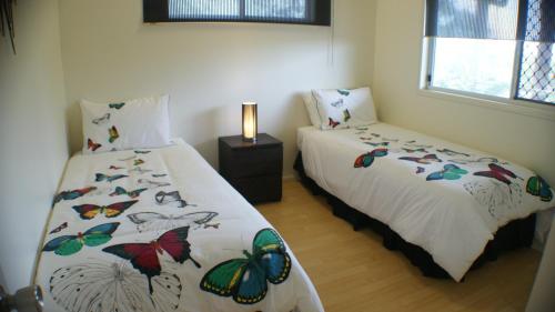 a bedroom with two beds with butterflies on the sheets at Tinaroo Sunset Retreat in Barrine