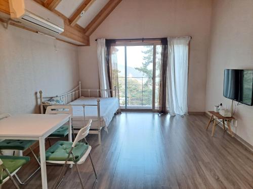 a room with a bed and a table and a television at The Viewpoint House in Namhae