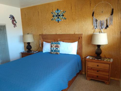 a bedroom with a blue bed with two lamps and a mirror at Mokee Motel in Bluff