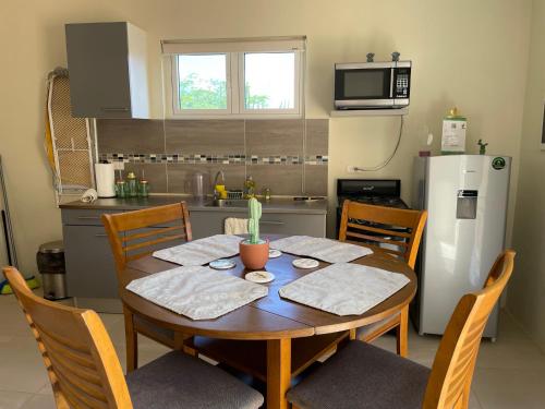 a kitchen with a wooden table with chairs and a refrigerator at LiCe Garden Aruba in Paradera