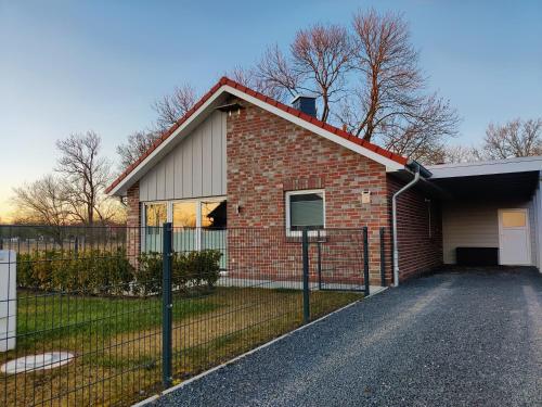 a brick house with a garage and a fence at Haus MeerErleben - Urlaub mit Hund an der Nordsee in Schweiburg