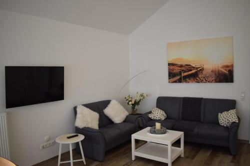 a living room with a couch and a tv at Haus MeerErleben - Urlaub mit Hund an der Nordsee in Schweiburg