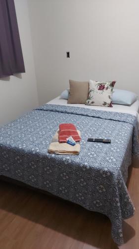 a bed with a blue comforter and towels on it at Quarto 201 in Juiz de Fora