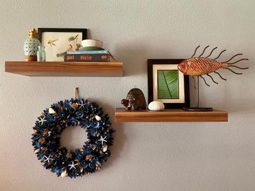 two wooden shelves with pictures and a wreath on a wall at Perfect for families and couples - Maui Sunset A-203 in Kihei