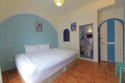 a bedroom with a white bed and a blue wall at Rainbow B&B in Dahan