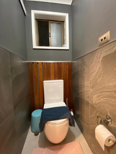 a bathroom with a toilet with a mirror and a window at Flamingo Rentals - Modern 2-bed unit with BBQ & SPA ideal for holiday and business travel in Mildura