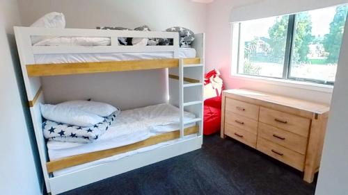 Zimmer mit Etagenbett, 2 Etagenbetten und einem Schreibtisch in der Unterkunft Solar on Snowmass Red Door in Ohakune