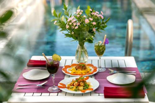 una mesa con dos platos de comida y copas de vino en Gioan Boutique Villa, en Hoi An