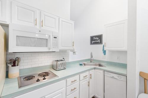 a white kitchen with white cabinets and a sink at Cannon beach vibes, steps to the beach,WIFI,3 full bedroom en suites with 3 fireplaces,Near Downtown in Cannon Beach