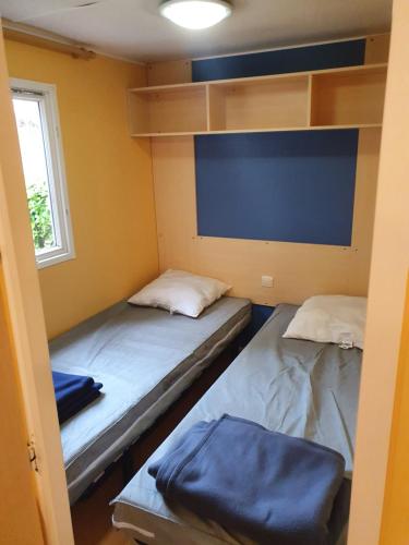 - 2 lits dans une petite chambre avec fenêtre dans l'établissement camping parc des roches, à Souzy-la-Briche