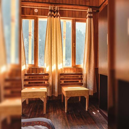 a room with two chairs and a window at ThePahadians Food & Stay in Jibhi