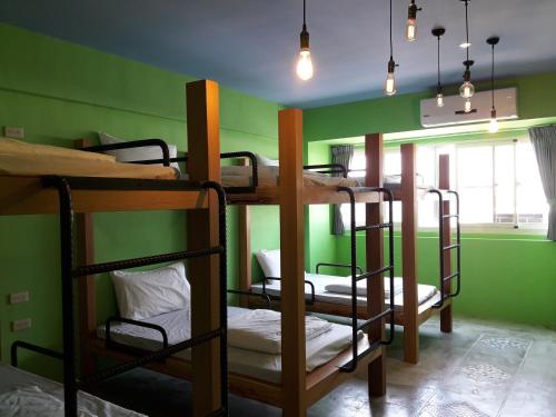 台東市的住宿－Peggy Home，一间设有三张双层床的客房,位于带绿色墙壁的房间