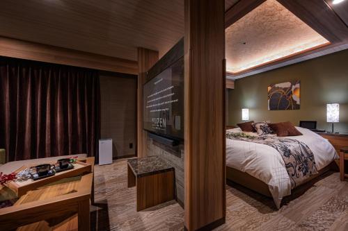 a hotel room with a bed and a television at ホテルゼン離宮平野 in Osaka