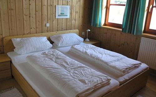 a bed with white sheets and pillows in a room at Ferienhaus Nr 11A2, Feriendorf Hagbügerl, Bayr Wald in Waldmünchen