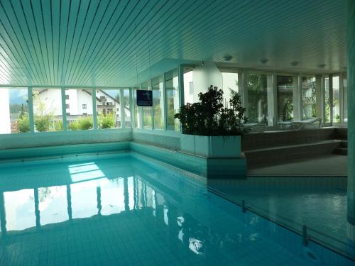 a large swimming pool in a building with windows at Ferienwohnung Murschetg in Laax