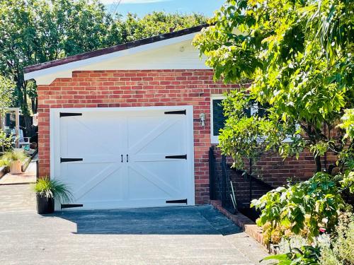 a large white garage with a brick building at Whitby Studio - Mairangi Bay Beach in Auckland