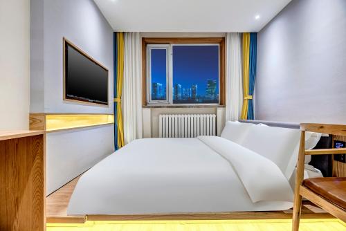 a bedroom with a large white bed and a window at Happy Dragon Universal Vacation Hotel - close to Universal Studio and Wanda Plaza,free shuttle to the Resort,Free Coffee,Laundry in Beijing
