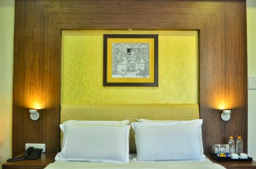 Hotel Arunachala في تيروفانمالي: سرير مع وسادتين وصورة فوق