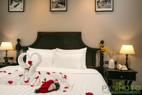 a bedroom with a bed with white sheets and roses at Hanoi Paradise Center Hotel & Spa in Hanoi