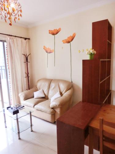 a living room with a couch and flowers on the wall at YuMi Gaopai in Guangzhou