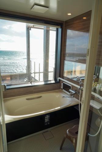 a bathroom with a tub and a window with the ocean at Sinori205 in Hakodate