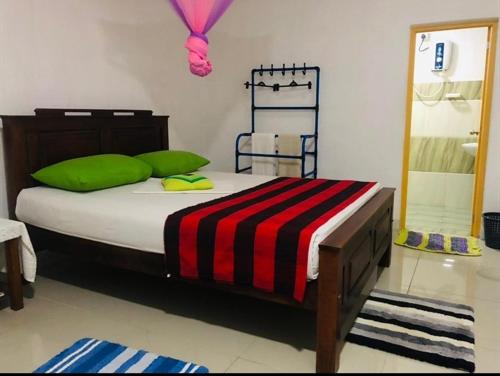 波隆納魯沃的住宿－ARANI HOMESTAY，一间卧室配有一张带绿色枕头的大床
