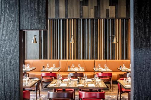 a dining room with tables and red chairs at InterContinental Perth City Centre by IHG in Perth