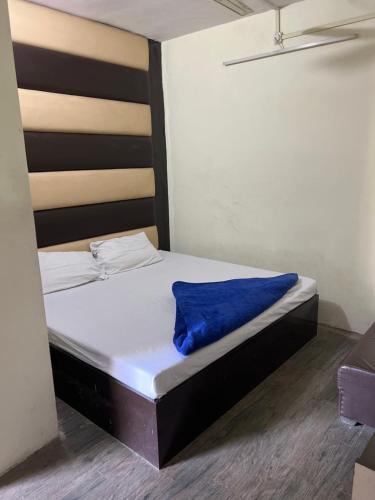 Una cama con una manta azul en una habitación en Hotel Abhishek, en v