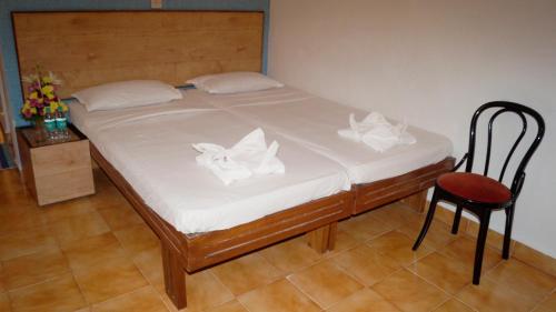 a bed with white sheets and a chair in a room at Time & Leisure Hotels in Candolim