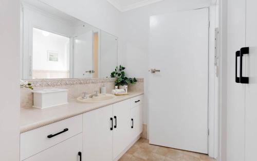 a white bathroom with a sink and a mirror at Islander Escape in Encounter Bay