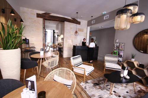 un restaurant avec des tables et des chaises et des personnes en arrière-plan dans l'établissement Hôtel de Tourny - Boutique Hôtel Bordeaux Centre, à Bordeaux