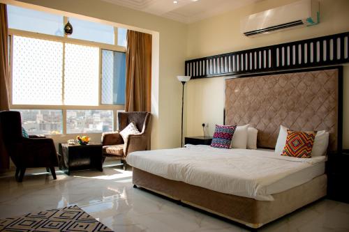 a bedroom with a large bed and a living room at Qasayed Hotel فندق قصائد in Salalah