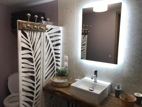 La salle de bains est pourvue d'un lavabo et d'un miroir. dans l'établissement L’Atelier de René Futuroscope, à Beaumont