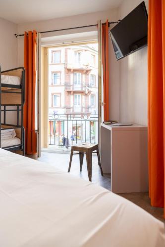 a bedroom with a bed and a window with orange curtains at Hotel Victoria in Strasbourg