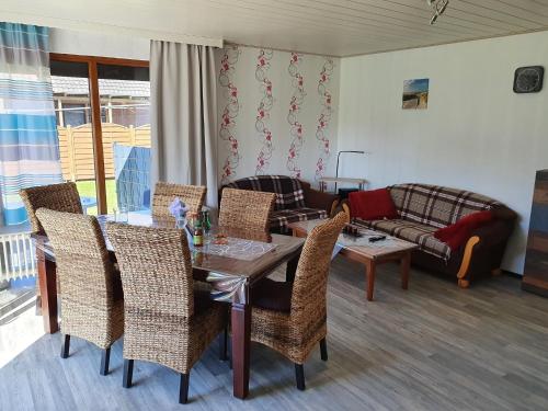 ein Wohnzimmer mit einem Tisch, Stühlen und einem Sofa in der Unterkunft Ferienhaus-Bogen-Glück in Osteel