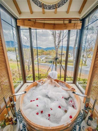 a man in a bath tub in a room with windows at Banyan Tree Huangshan in Huangshan