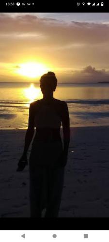 a woman standing on the beach at sunset at Yohana Cottage in Tual