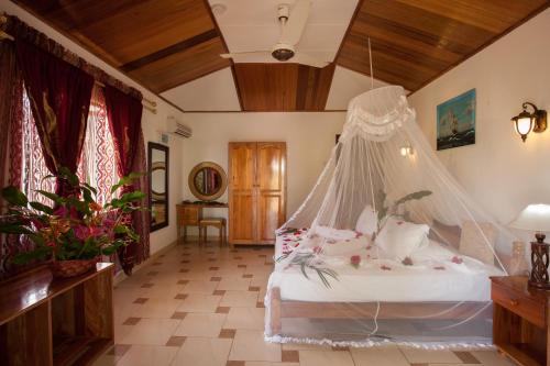 a bedroom with a bed with a mosquito net at Etoile Labrine Guest House in La Digue