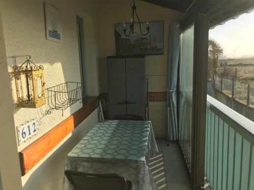 Cette chambre dispose d'un balcon avec une table et une fenêtre. dans l'établissement Appartement cosy en résidence privée avec vue mer, à Soulac-sur-Mer
