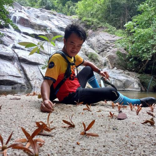 a young boy sitting on the ground next to a river at โฮมสเตย์บ้านนายสิงโตเขาคูหา in Ban Khu Ha Nai (1)