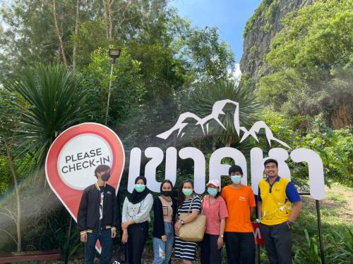 a group of people standing in front of a sign at โฮมสเตย์บ้านนายสิงโตเขาคูหา in Ban Khu Ha Nai (1)