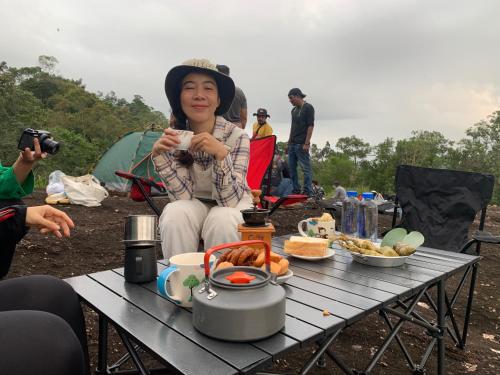 a woman sitting at a table with a cup of food at โฮมสเตย์บ้านนายสิงโตเขาคูหา in Ban Khu Ha Nai (1)
