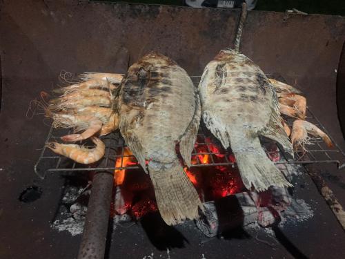 three fish are cooking on a grill with fire at โฮมสเตย์บ้านนายสิงโตเขาคูหา in Ban Khu Ha Nai (1)