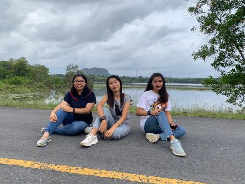 three women are sitting on the side of a road at โฮมสเตย์บ้านนายสิงโตเขาคูหา in Ban Khu Ha Nai (1)