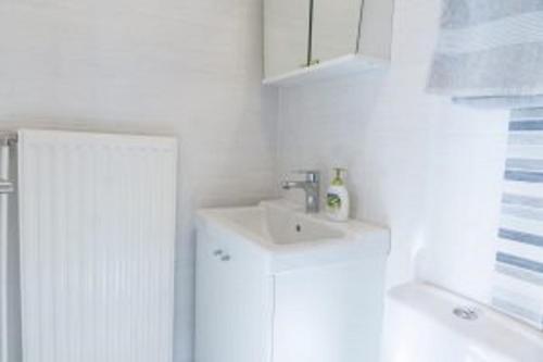 Baño blanco con lavabo y espejo en BAUERs Gästehaus en Obersiebenbrunn