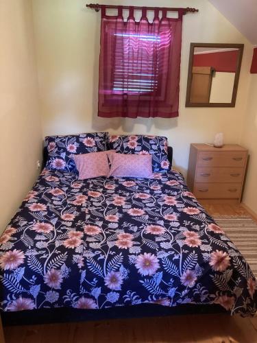 a bedroom with a bed with a floral comforter at Vineyard Cottage Slanc in Metlika